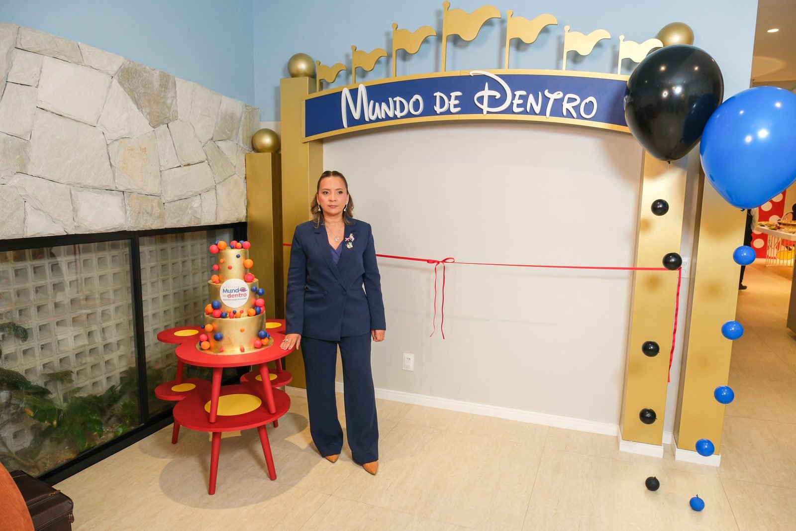 Kennya Martins na inauguração do Instituto Mundo de Dentro, ao lado do bolo comemorativo e da fita de inauguração