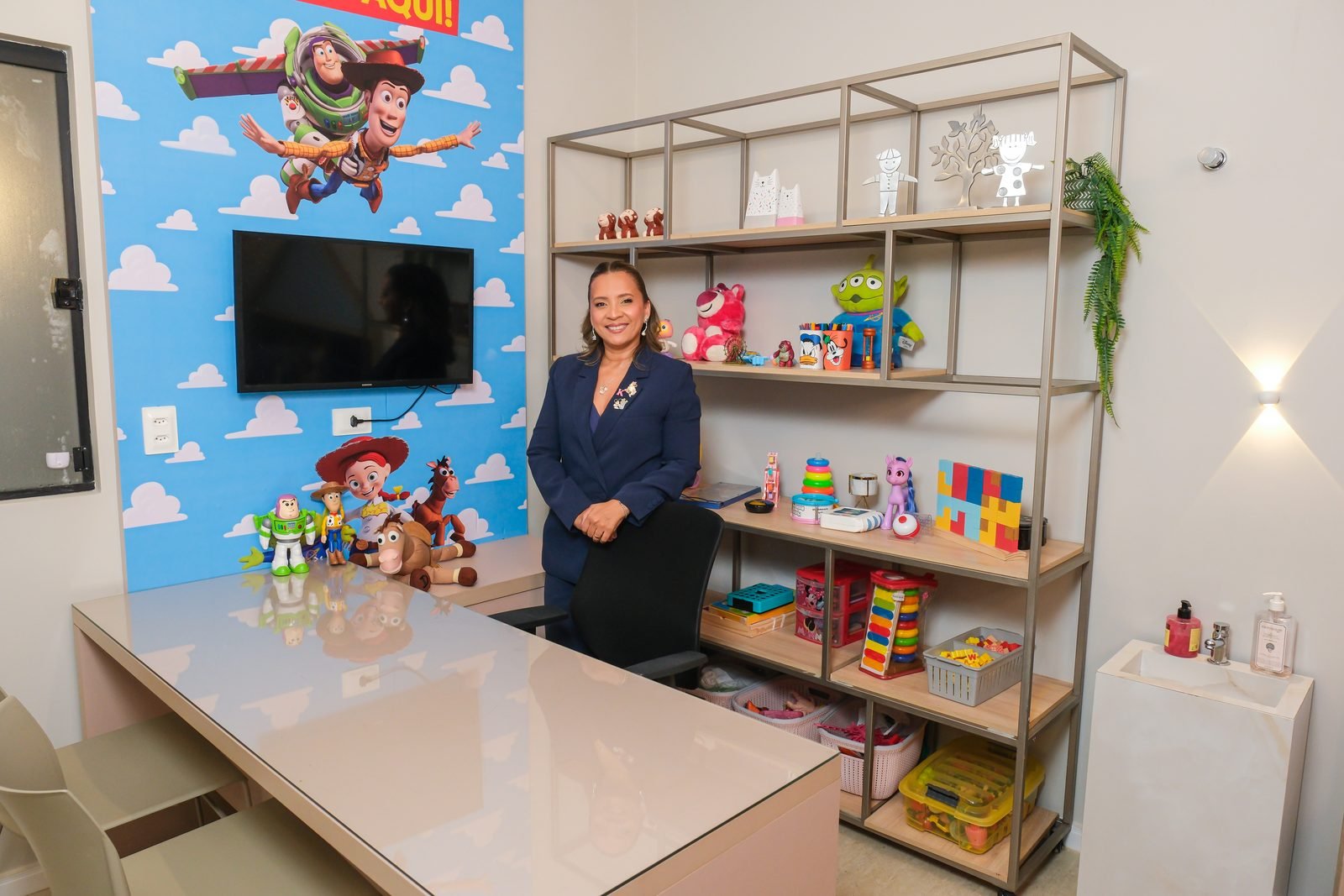 Kennya Martins na sala de psicologia infantil do Instituto Mundo de Dentro, entre a mesa e a estante de brinquedos